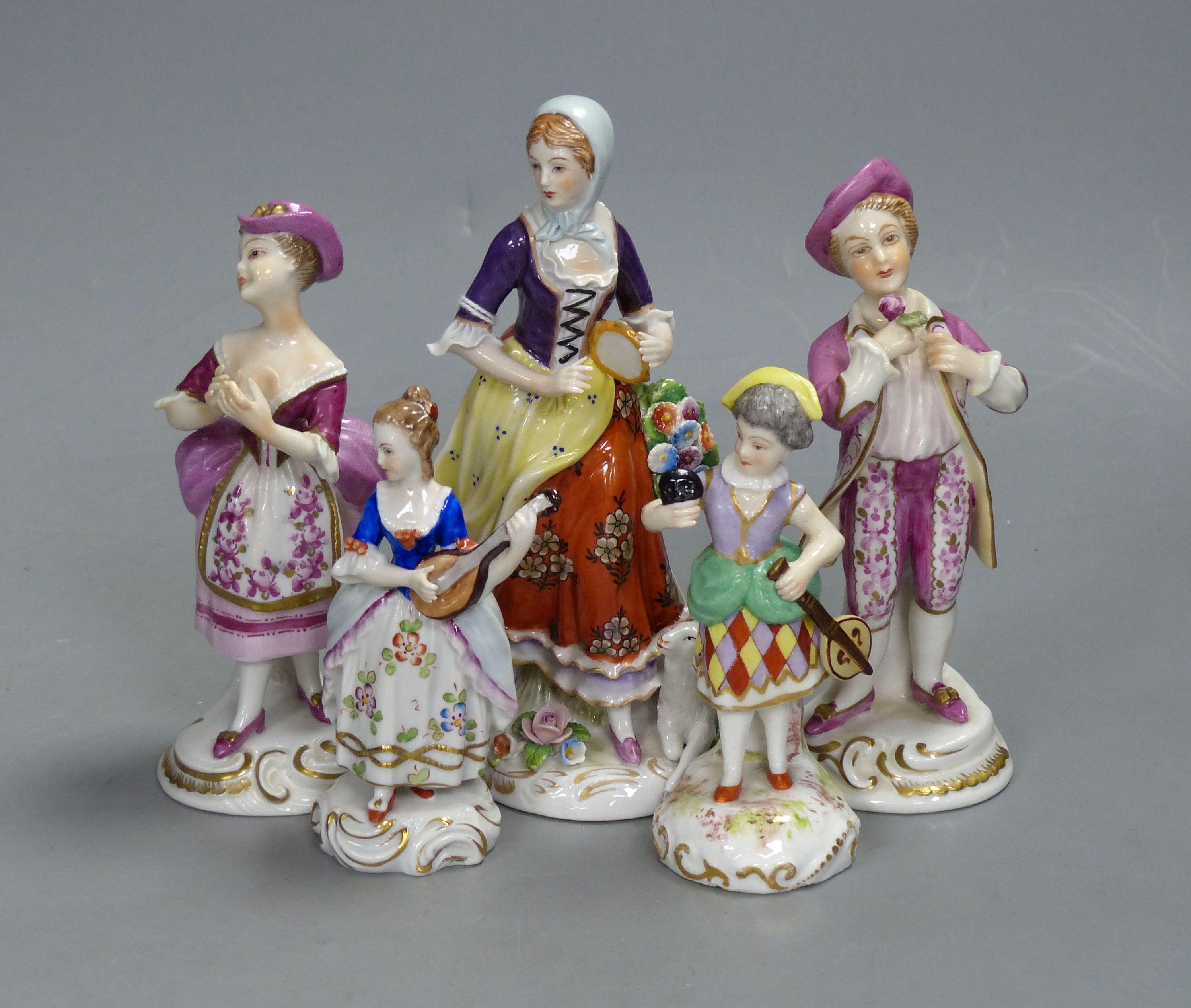 A German porcelain figure of a masked harlequin with stringed instrument and four other Continental porcelain figures, tallest 16cm